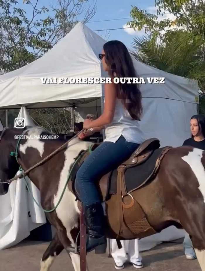 Melissa Said com cabelos castanhos, montada em um cavalo branco e marrom.